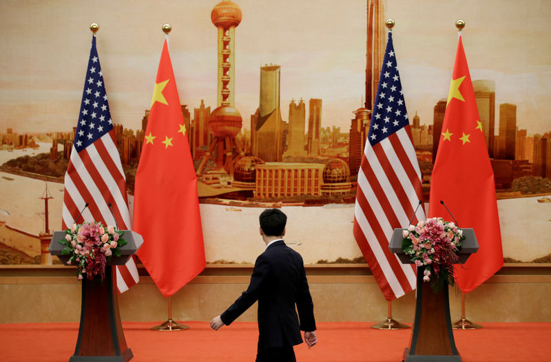 © Reuters. FILE PHOTO: A staff member walks past U.S. and Chinese flags placed for a joint news conference in Beijing