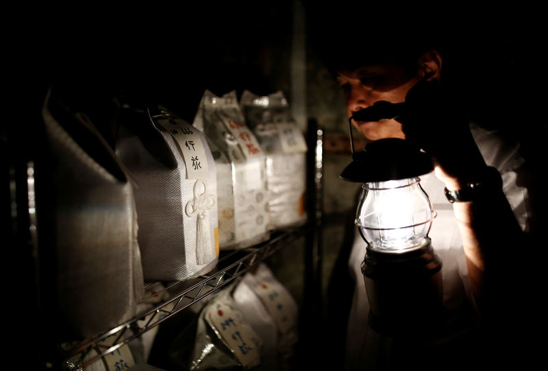 © Reuters. Kazuyuki Kitami, a city official of Yokosuka, holds a lantern as he visits a facility which keeps the unclaimed burial urns containing ashes of the dead in Yokosuka