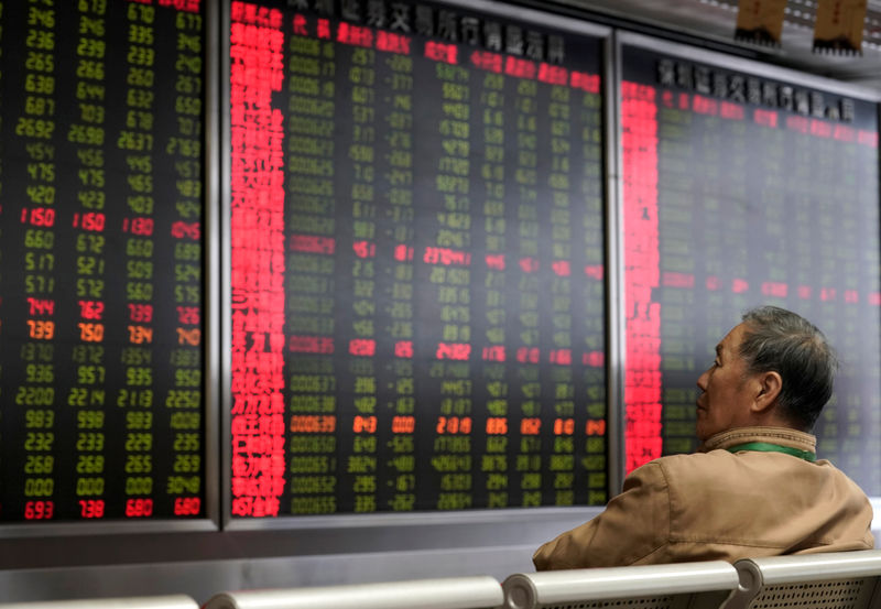 © Reuters. FILE PHOTO: An investor watches a board showing stock information at a brokerage office in Beijing