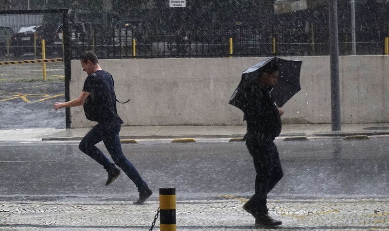 © Reuters. Homem corre durante chuva no Rio de Janeiro