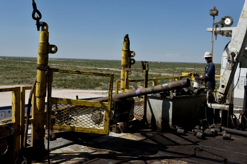 © Reuters. FILE PHOTO: A drilling crew member raises drill pipe onto the drilling rig floor on an oil rig in the Permian Basin near Wink