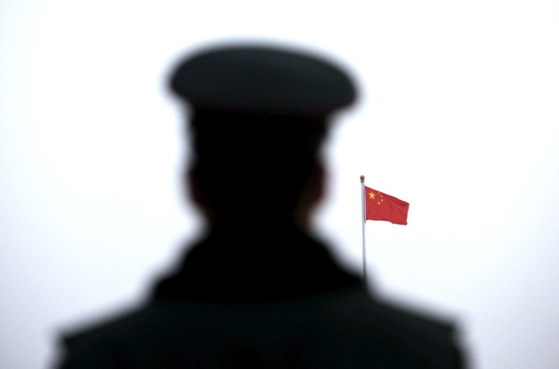 © Reuters. A paramilitary policeman watches a flag-raising ceremony at Tiananmen Square ahead of the opening session of the National People's Congress in Beijing, China