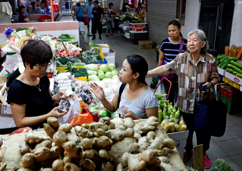 © Reuters. FILE PHOTO: People shop for vegetables at a wet market in Singapore