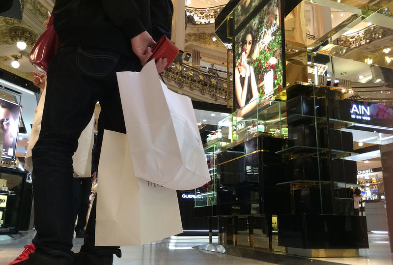 © Reuters. A customer carries shopping bags with purchases in a department store in Paris