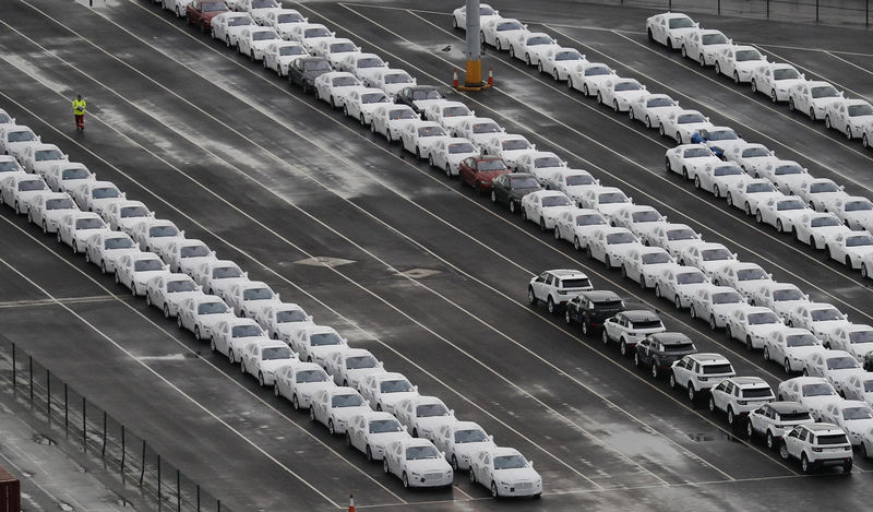 © Reuters. A worker walks between rows of Jaguar and Land Rover cars as they wait to be shipped from Peel Ports container terminal in Liverpool