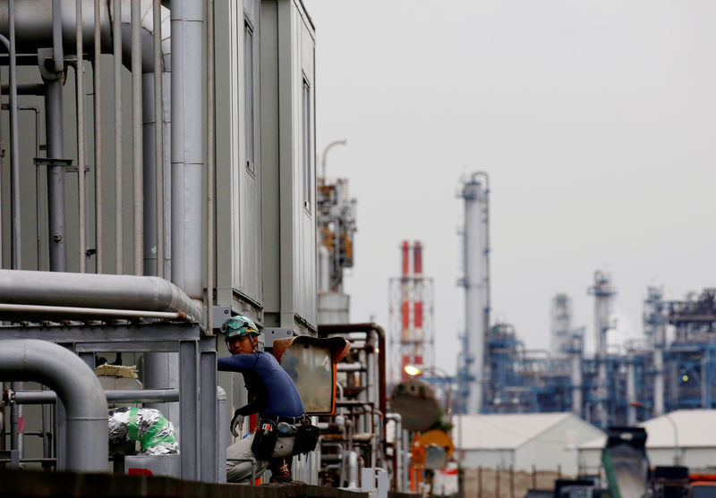 © Reuters. A worker is seen in front of facilities and chimneys of factories at the Keihin Industrial Zone in Kawasaki