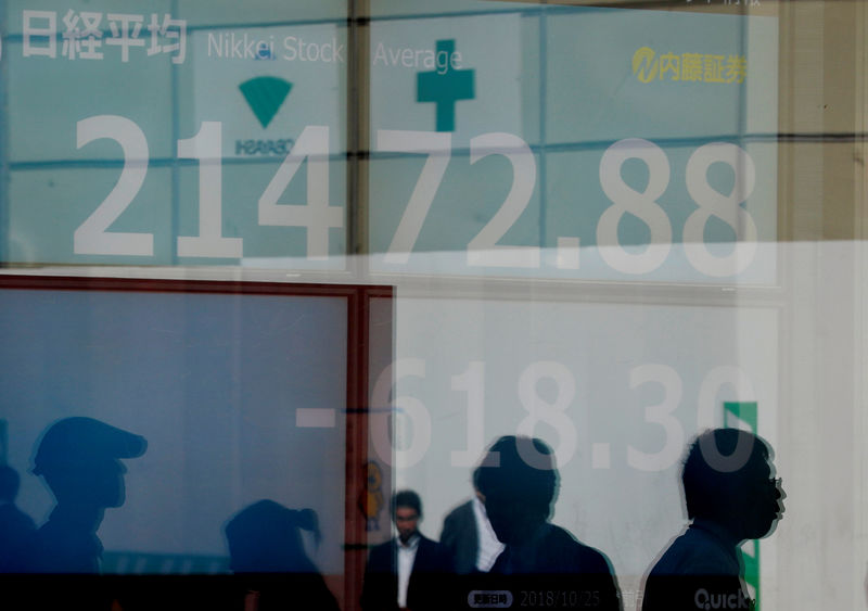 © Reuters. Pedestrians are reflected on an electronic board showing Japan's Nikkei average outside a brokerage in Tokyo