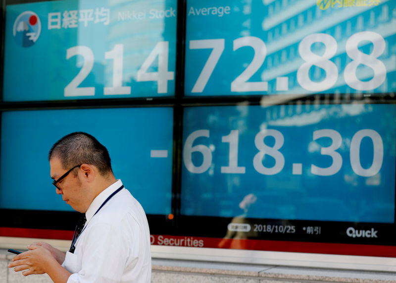© Reuters. A man stands in front of an electronic board showing Japan's Nikkei average outside a brokerage in Tokyo
