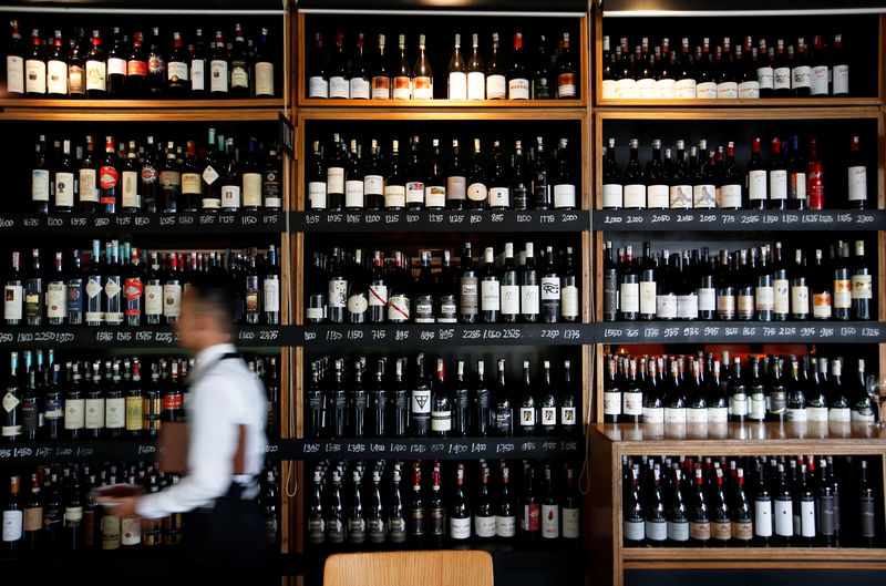 © Reuters. A server passes a wine rack at the Cork & Screw restaurant in Jakarta