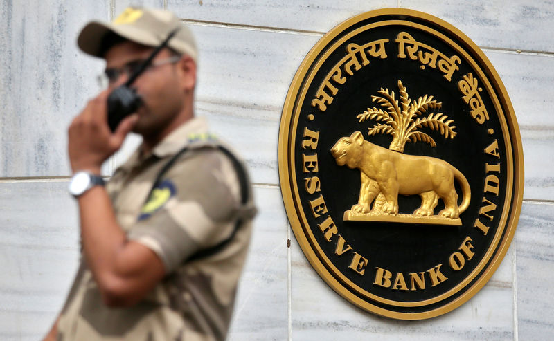 ©路透社。 文件照片：一名警卫站在孟买总部外的印度储备银行（RBI）标志旁边