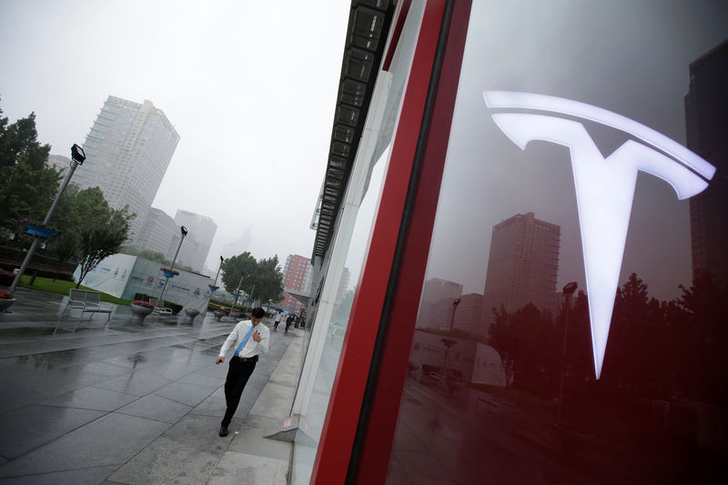 © Reuters. A man walks near a logo of Tesla outside its China headquarters in Beijing