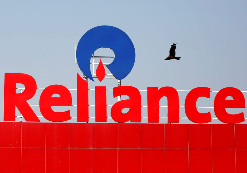 © Reuters. FILE PHOTO: A bird flies past a Reliance Industries logo installed on its mart in Ahmedabad