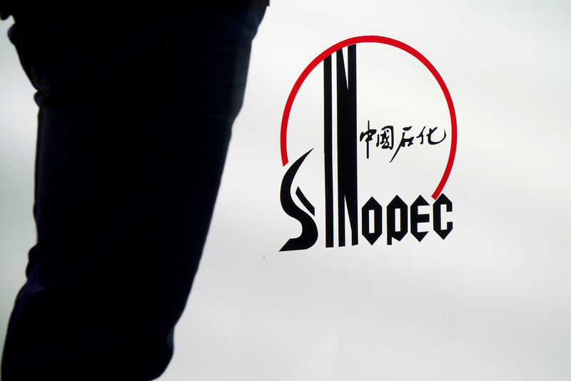 © Reuters. Man stands next to a logo of Sinopec at an expo on rubber technology in Shanghai