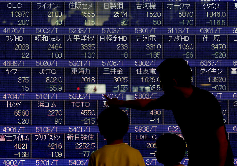 © Reuters. A man talks to his children in front of an electronic stock quotation board outside a brokerage in Tokyo