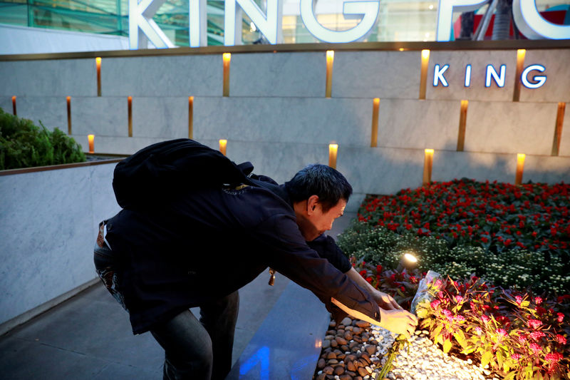 © Reuters. A man lays flowers in front of King Power's head office in Bangkok