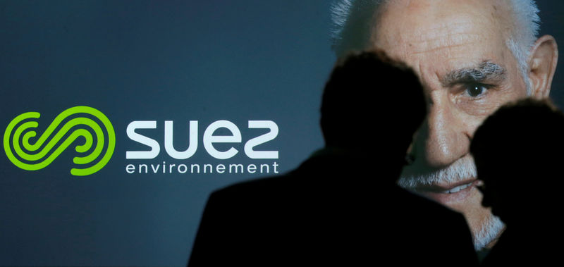 © Reuters. FILE PHOTO: People are silhouetted in front of the new logo of French waste and water company Suez Environnement during a presentation in Paris