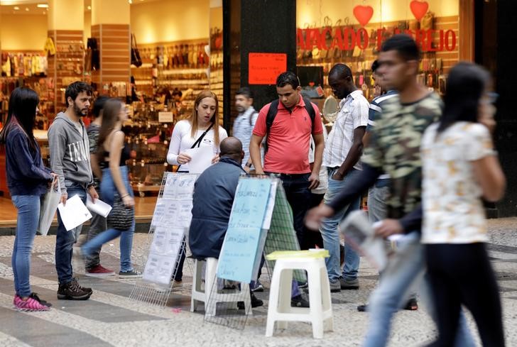 © Reuters. Pessoas olham para listas de vagas de emprego postadas em uma rua no centro de São Paulo, Brasil