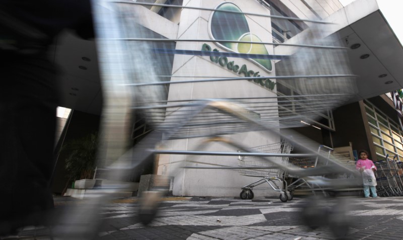 © Reuters. Trabalhador empurra carrinho de compras na entrada do supermercado Pão de Açúcar em São Paulo
