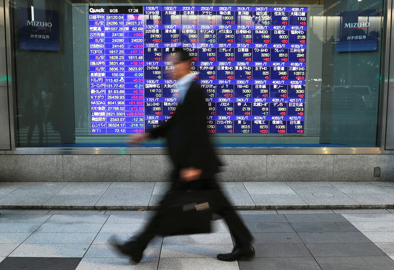 © Reuters. Passersby walk past in front of an electronic stock quotation board outside a brokerage in Tokyo