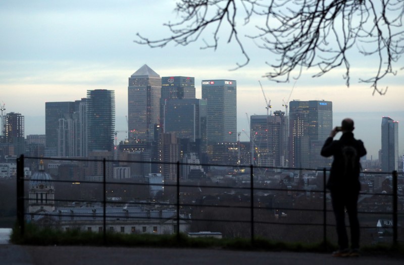 © Reuters. A man takes a photograph of the Canary Wharf financial district from Greenwich Park in London