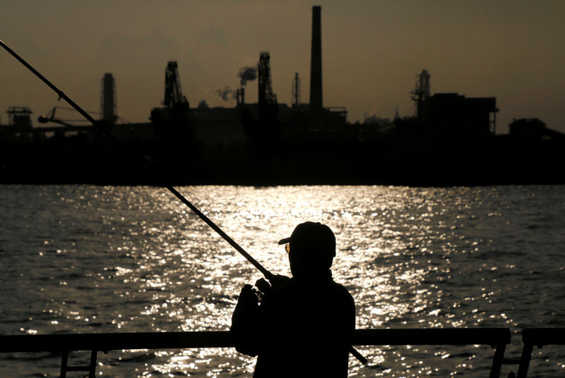 © Reuters. A man fishes near a factory at the Keihin industrial zone in Kawasaki, Japan