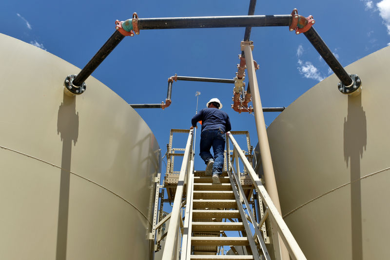 © Reuters. FILE PHOTO: Lease Operator Jon Pearson inspects oil tanks at a production facility owned by Parsley Energy in the Permian Basin near Midland