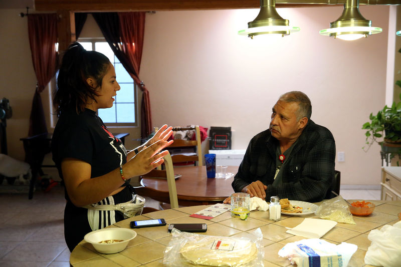 © Reuters. La voluntaria Bea Nevarez habla con el potencial votante José Alberto Moreno en su cocina durante una campaña puerta a puerta en Tucson, Arizona, EEUU.