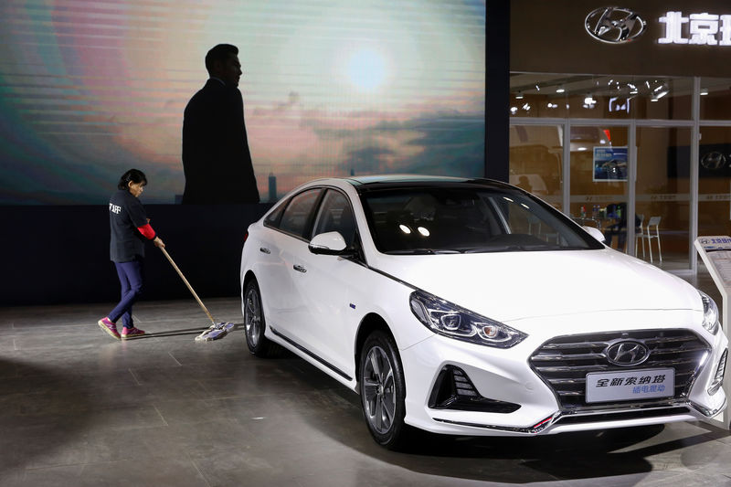 © Reuters. Worker cleans the floor next to a Sonata hybrid at a booth of Beijing Hyundai Motor in Beijing