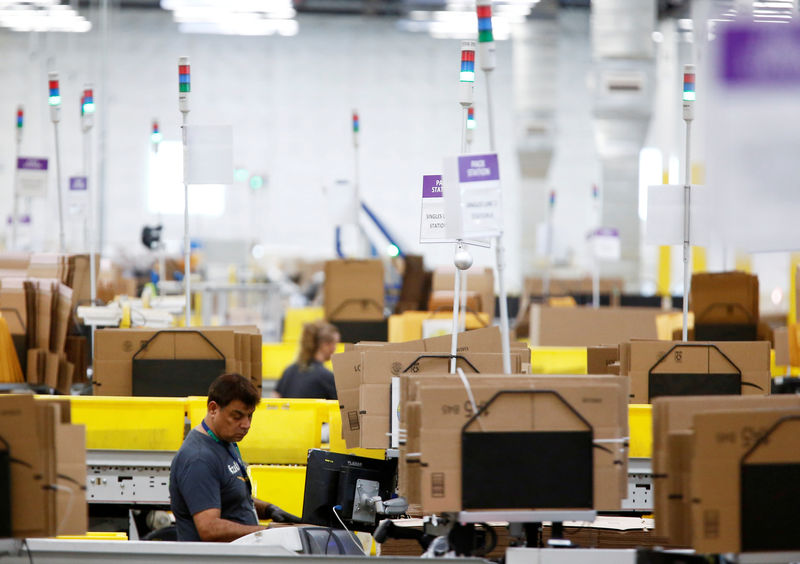© Reuters. FILE PHOTO: Employees work at packing stations on the main floor at the Amazon fulfillment center in Kent