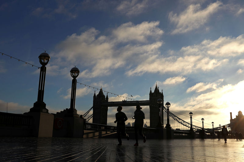 © Reuters. People run past Tower Bridge in the early morning autumnal sunshine, in London