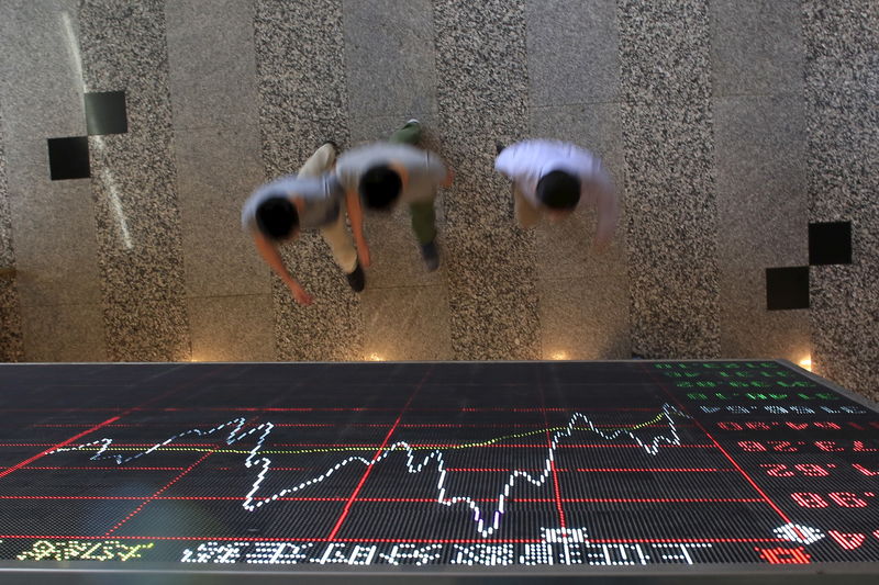 © Reuters. FILE PHOTO - People walk under an electronic board showing stock information at the Shanghai Stock Exchange in Lujiazui Financial Area in Shanghai