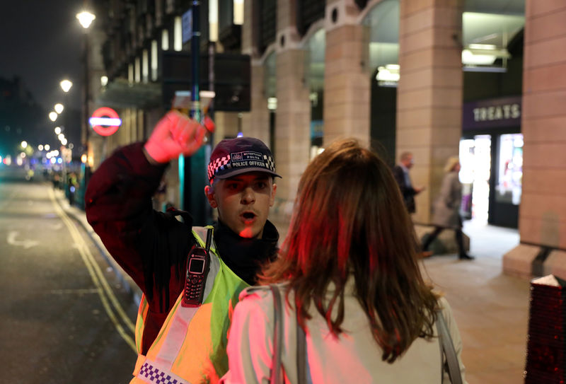 © Reuters. Agente policial conversa com mulher próximo ao Parlamento no momento em que a polícia investiga pacote suspeito, no centro de Londres