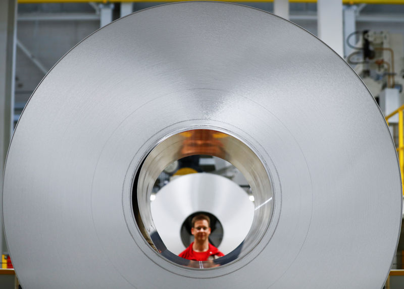 © Reuters. A worker poses for a photo through an aluminium coil during opening of a production line for the car industry at a branch of Norway's Hydro aluminum company in Grevenbroich