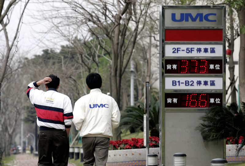 © Reuters. FILE PHOTO: Men walk past a signboard of chipmaker United Microelectronics Corp (UMC) in Hsinchu