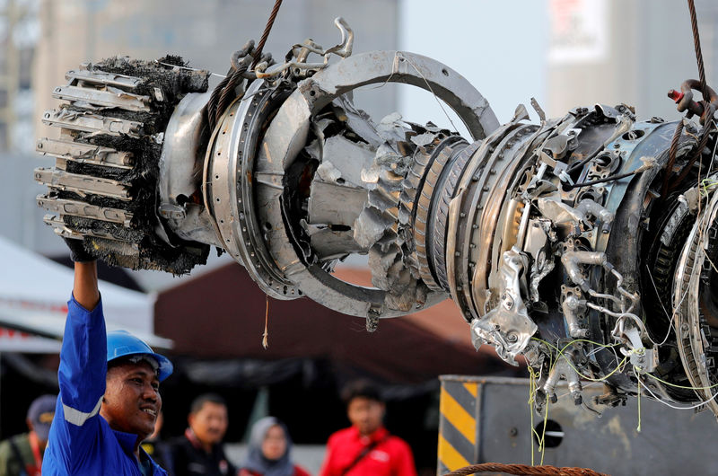 © Reuters. FILE PHOTO: A worker assists his colleague during the lifting of a turbine engine of the Lion Air flight JT610 jet, at Tanjung Priok port in Jakarta