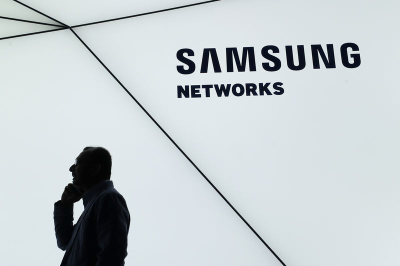 © Reuters. Homem usa telefone em frente e logo da Samsung