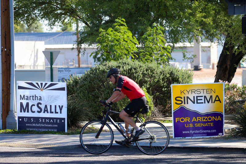 © Reuters. FILE PHOTO: A man rides a bicycle past campaign signs for Arizona U.S. senatorial candidates Krysten Sinema and Martha McSally following the U.S. Midterm elections in Scottsdale, Arizona