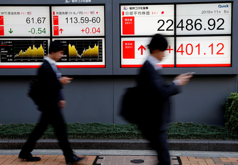 © Reuters. Passersbys walk past an electronic board showing Japan's Nikkei average outside a brokerage in Tokyo
