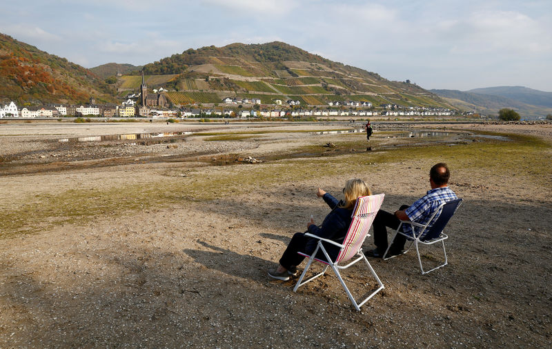 © Reuters. FILE PHOTO: A couple sit on their camping chairs amid the river bed of the dried out Rhine near Bacharach