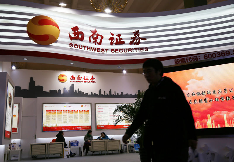 © Reuters. Man walks past a booth of Southwest Securities at a finance expo in Beijing