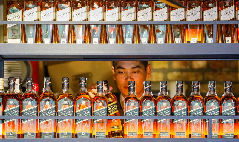 © Reuters. FILE PHOTO: A bartender takes a bottle of Johnnie Walker whisky at Barmaglot bar in Almaty