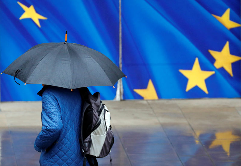 © Reuters. A man with an umbrella walks past the EU Commission headquarters in Brussels