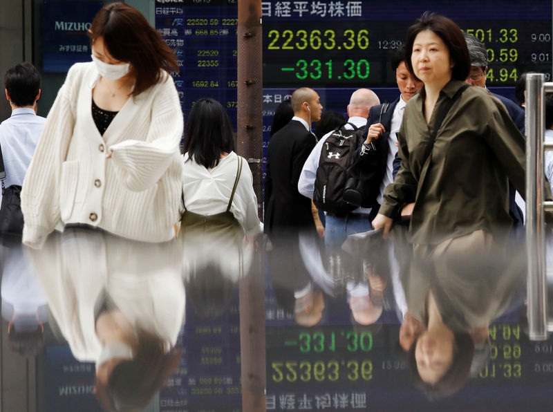 © Reuters. People walk past an electronic board showing Japan's Nikkei average outside a brokerage in Tokyo