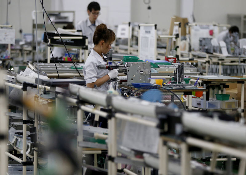 © Reuters. FILE PHOTO: Employees work an assembly line at a factory of Glory Ltd., a manufacturer of automatic change dispensers, in Kazo, north of Tokyo