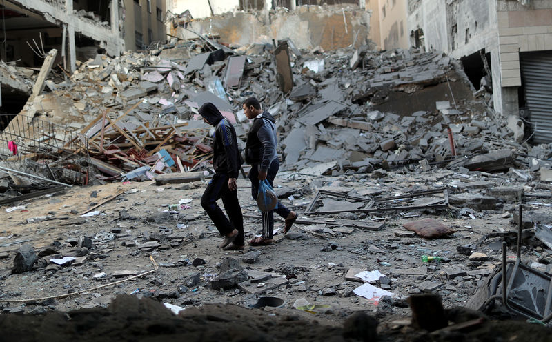 © Reuters. Palestinos passam por destroços de prédio destruído por ataque aéreo israelense em Gaza