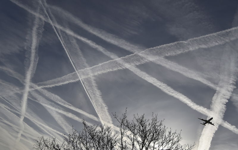 © Reuters. A passenger plane flies through aircraft contrails in the skies near Heathrow Airport in west London
