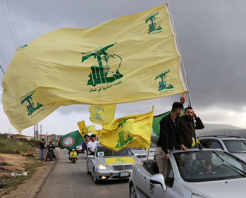 © Reuters. FILE PHOTO: A supporter of Lebanon's Hezbollah gestures as he holds a Hezbollah flag in Marjayoun