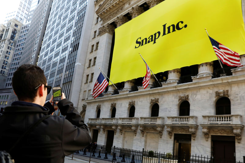 © Reuters. A man takes a photograph of the front of the New York Stock Exchange (NYSE) with a Snap Inc. logo hung on the front of it shortly before the company's IPO in New York