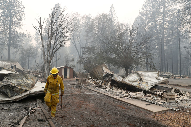 © Reuters. A Cal Fire firefighter walks between homes destroyed by the Camp Fire in Paradise