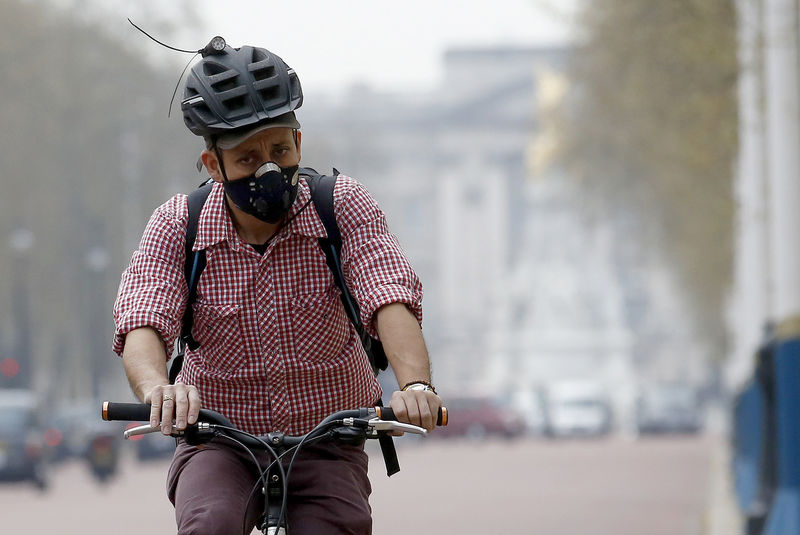 © Reuters. FILE PHOTO: A cyclist wears a mask as he cycles near Buckingham Palace in London